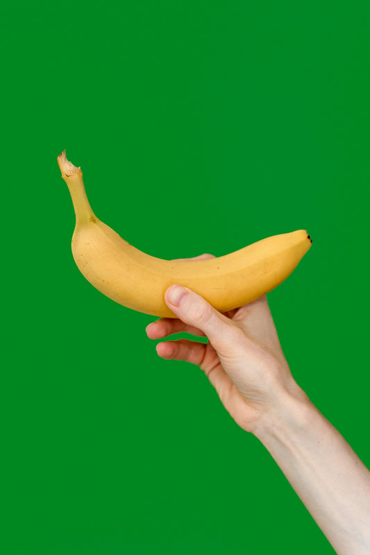 a hand holding a banana on a green background