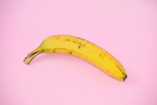 A yellow banana sitting on top of a pink surface